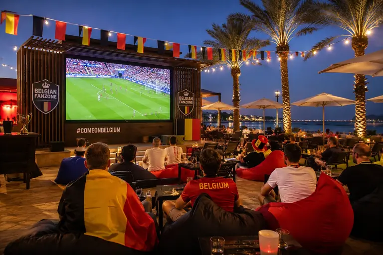 Belgian FanZone at InterContinental Doha Beach and Spa with fans watching a live football match outdoors.